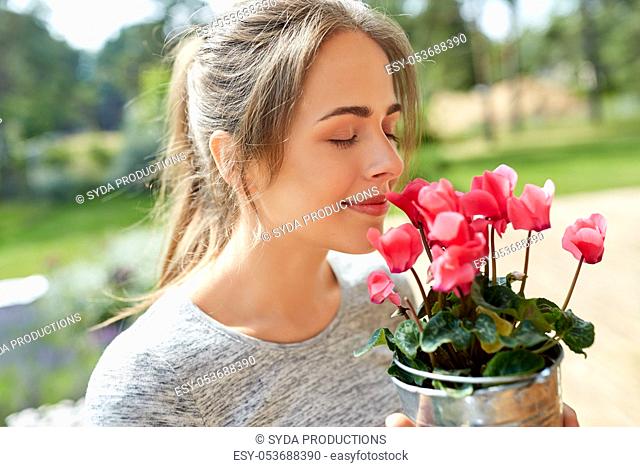 young woman with cyclamen flowers at summer garden