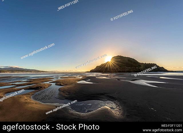 New Zealand, Tongaporutu, Clear sky over sandy coastal beach at sunset with¶ÿMotuotamatea¶ÿisland in background
