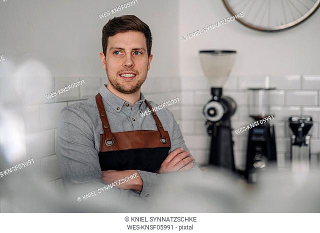Barista wearing apron, standing in coffee shop