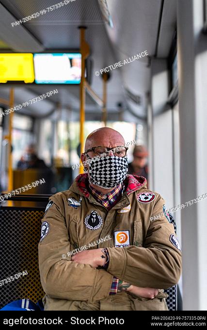 20 April 2020, Saxony, Dresden: Michael Riedel, a nurse and healthcare worker, sits in a tram on his way to work in the morning and wears a mouth guard