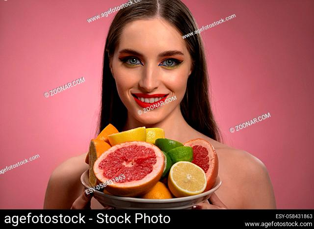 Fruit salad for cosmetic mask for girl face with natural make up and bare shoulders. Healthy pure skin model isolated on black background