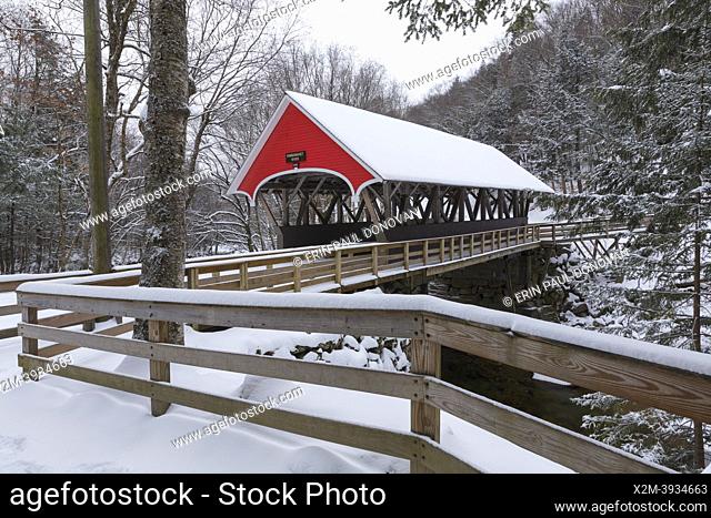 The Flume Covered Bridge in Franconia Notch, New Hampshire covered in snow on an autumn morning. This picturesque bridge crosses the Pemigewasset River