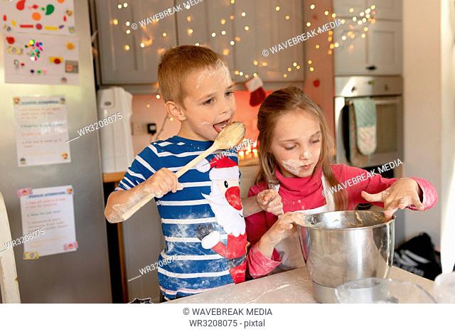 Siblings preparing and tasting the batter for Christmas cookies