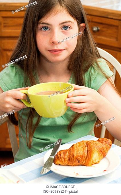 Girl drinking hot chocolate with croissant