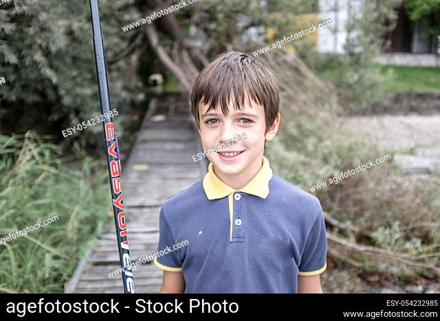 Child on a pier holding fishing rod, Lake Maggiore, Italy
