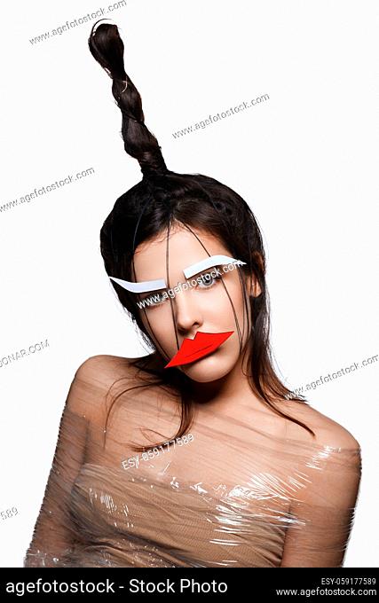 Beautiful young woman with odd fancy hairstyle and eyebrows and lips paper cutouts on face. Beauty shot isolated on background. Copy space