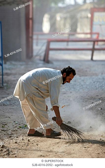 Afghan Man Sweeps a Dirt Road