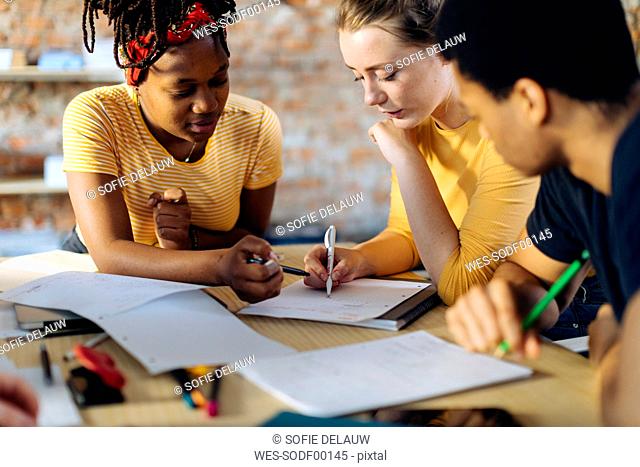 Young people sitting together at table and taking notes