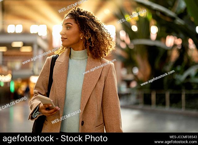 Young woman holding mobile phone at station