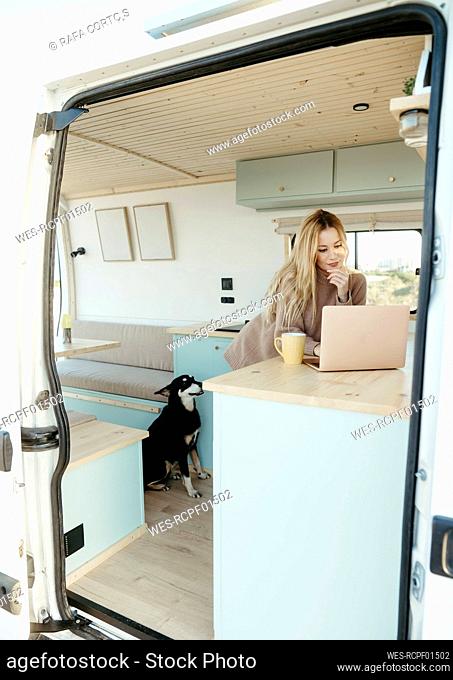 Digital nomad using laptop leaning on table inside motor home