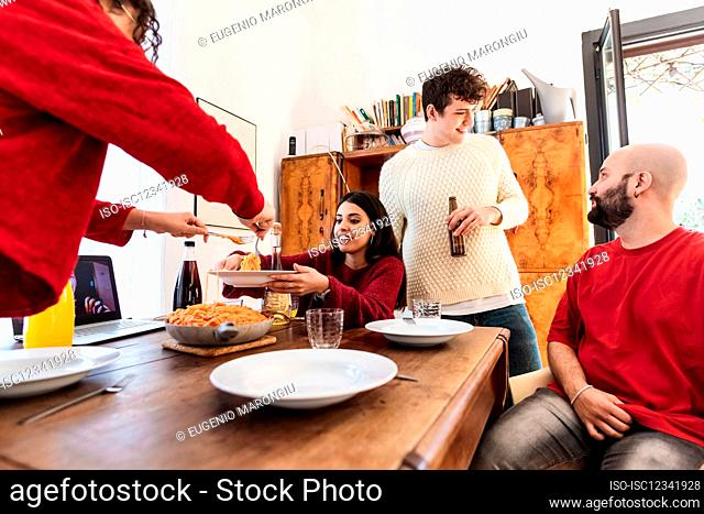 Amigos compartiendo comida en casa, con videollamada