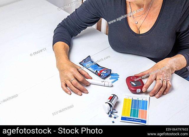 Top view of woman preparing device for measuring blood sugar on the white table