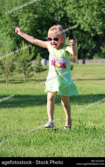 Happy little girl running in city park. Positive childish emotions. Child running along path smiling and rejoicing. Happy childhood