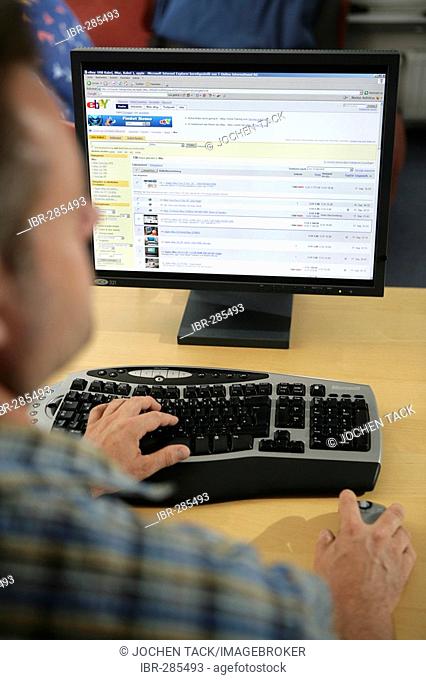 DEU, Germany : Man is sitting at a computer, surfing the internet. Ebay site. |