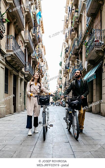 Couple pushing e-bikes exploring the city