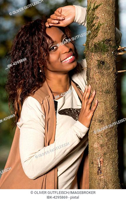 Dark-skinned young woman in autumn outfit in the forest