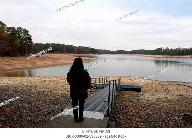Young woman looking out on shock at the water level of Lake Sidney Lanier during the worst drought in Georgia history