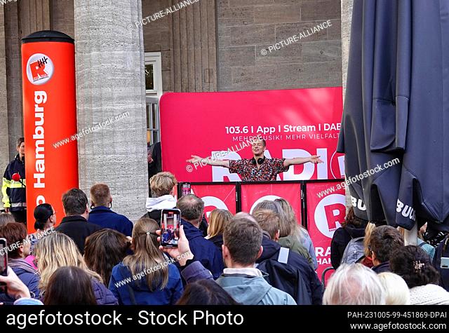 05 October 2023, Hamburg: Frans Zimmer aka Alle Farben (back), DJ and music producer, DJs at a concert in front of a café in downtown Hamburg