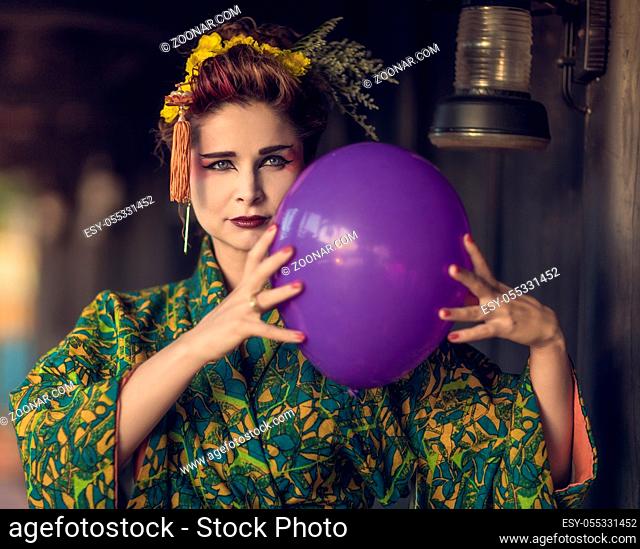 Fine art portrait of european woman in Japanese Geisha style wearing kimono with balloon