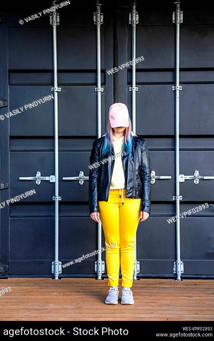 Portrait of young woman with dyed hair in front of black container