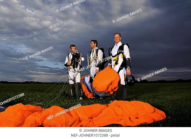 Skydivers standing and holding parachutes