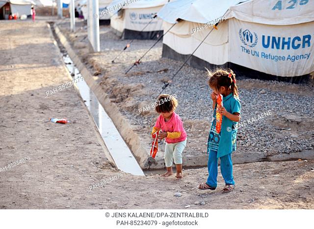 A boy and a girl run down a gravel path between refugee accommodations in the Debaga refugee camp between Mosul and Erbil, Iraq, 18 October 2016