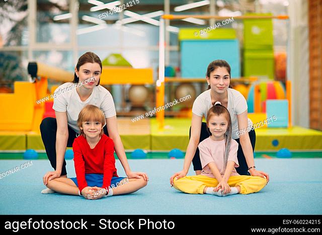 Kids girl and boy doing stretching exercises in gym at kindergarten or elementary school. Children sport and fitness concept