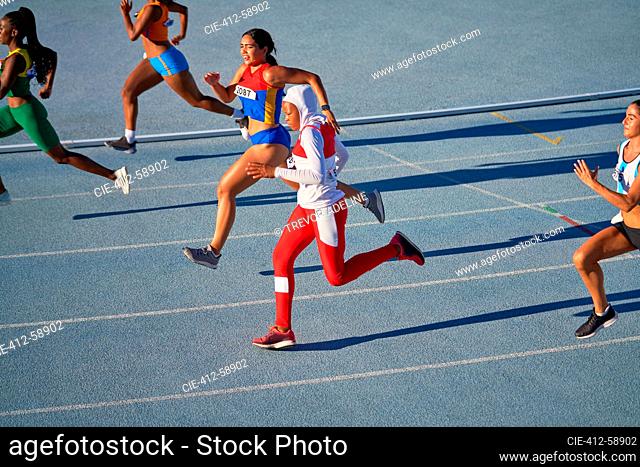 Atletas de pista y campo femeninos que se ejecutan en competición en pista soleada