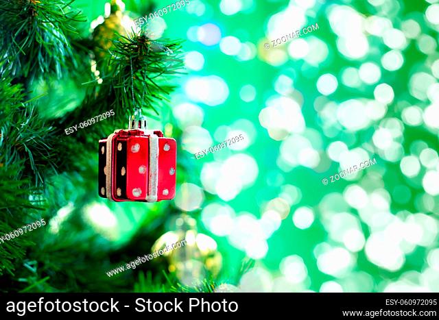 Christmas decoration toy red gift box hanging on a branch of a christmas tree, sparkling holiday background copy space design for postcard or leaflet