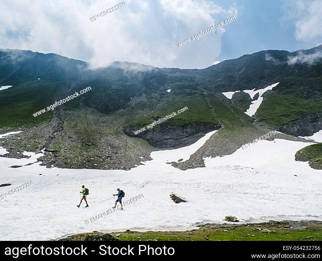 Hikers on snowfield, Val Formazza, Italy
