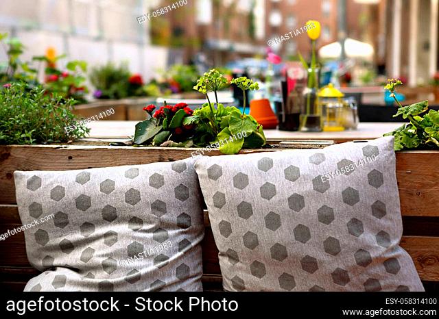 European street cafe with flowers on the table and cute pillows on the seat place in summer sunny day