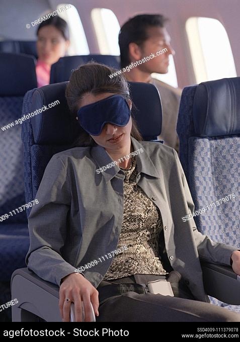 Young woman sleeping on airplane with eye mask