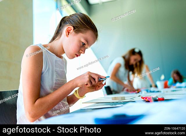 Young girl learning on the course of architectural design for children - preparing architectural model