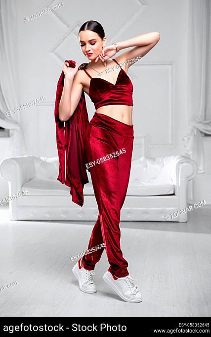 Sexy woman dressed in a burgundy velvet suit posing in the studio
