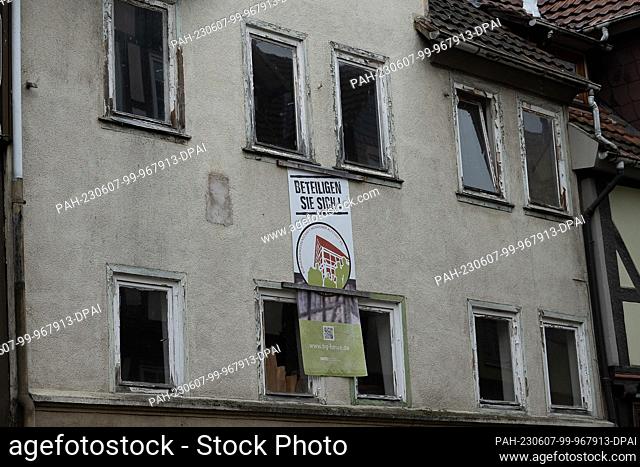 PRODUCTION - 05 May 2023, Lower Saxony, Hann. Münden: The old facade with a poster ""Get involved!"" makes a residential building purchased by...
