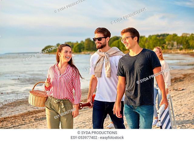 happy friends walking along summer beach