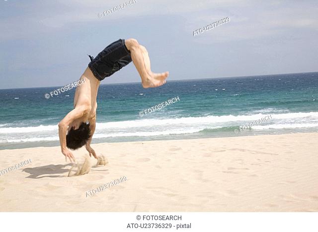 Japanese man doing gymnastics on a beach