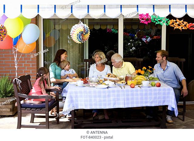 A multi-generational family having a celebration breakfast, outdoors