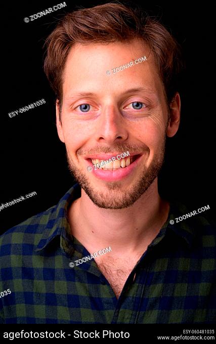 Studio shot of handsome bearded hipster man with brown hair against black background