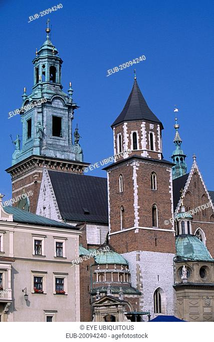 Detail of Wawel Cathedral exterior with clock tower above second tower and series of domed and pointed rooftops