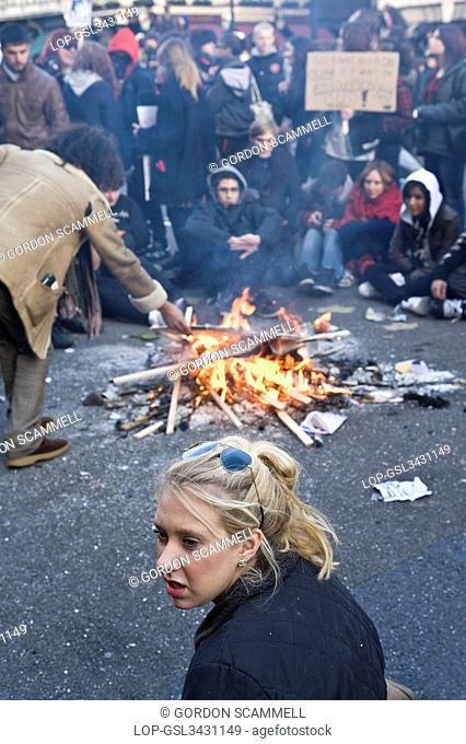 England, London. Students sitting around a bonfire in a street during a student demonstration