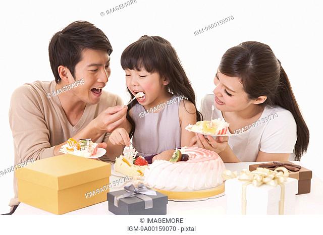 Young family elebrating birthday with smile and eating cakes together