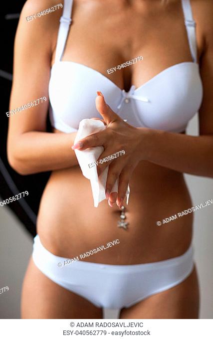 Young woman in panties and bra clean hands with wet wipes, body breast lingerie in blurred background