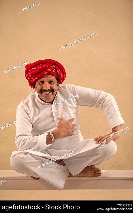 A HAPPY TURBANED VILLAGER SITTING AND LOOKING AT CAMERA
