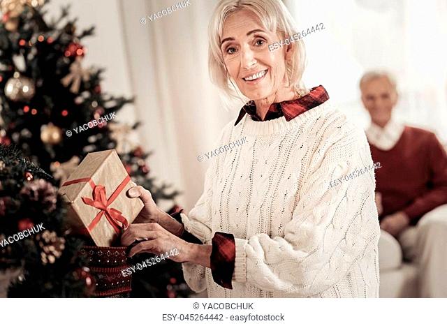 Our tradition. Amazing female person keeping smile on her face and holding box in right hand while looking on camera