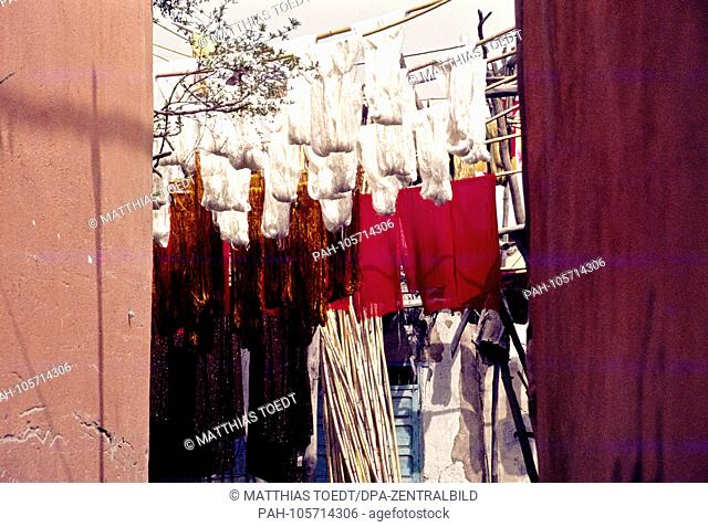 Freshly dyed wool is hung up on poles in a dyehouse in the old town of Marrakech for drying in the air, analogue undated photograph from March 1985