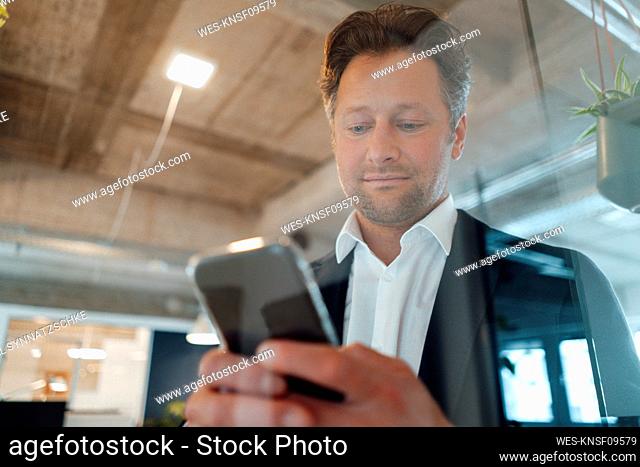 Mature businessman using smart phone in office