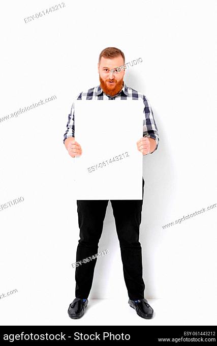 handsome man with beard holding big white card. empty blank board