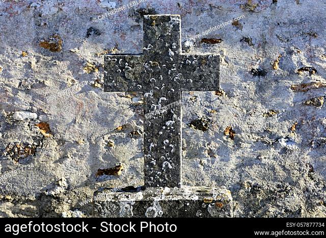 Stone cross on a gravestone along a stone wall. Coulommes. Seine et Marne. France. Europe
