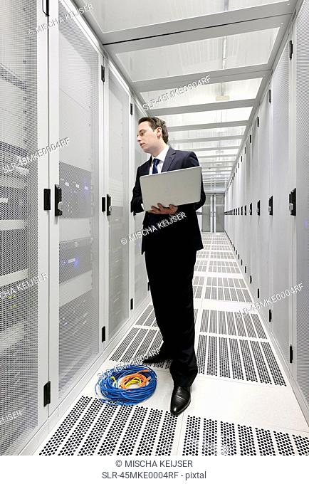 Businessman using laptop in server room